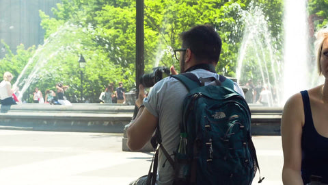 photographer taking pictures in Washington Square Park on summer day - water sprinklers spraying in center - NYC