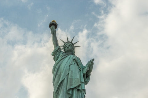 Statue of Liberty - medium shot at upward angle over blue sky with clouds on bright sunny day