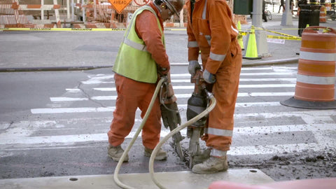 construction workers in orange suits drilling into concrete in slow motion - 1080 HD in NYC