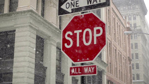 snowing with all way stop sign and one way arrow in snow storm blizzard on street in NYC