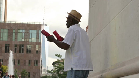 man shaking shakers and singing in Washington Square Park in summer under arch in NYC