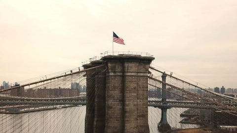 American flag on Brooklyn Bridge waving - aerial circling toward Brooklyn side of Bridge in NYC 1080 HD