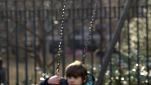 close-up of boy and girl swinging in playground, kids on swings in slow motion, tired children hanging out in Washington Square Park in 4K and 1080 HD in NYC