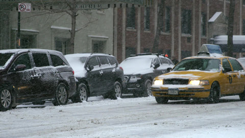 people crossing street past yellow taxi cab in Manhattan blizzard snow storm New York City NYC