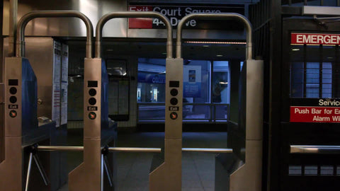tracking shot of subway station turnstiles in slow motion - woman exiting in summer