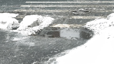 couple walks through ice and snow puddle in blizzard snowing on street in cold winter