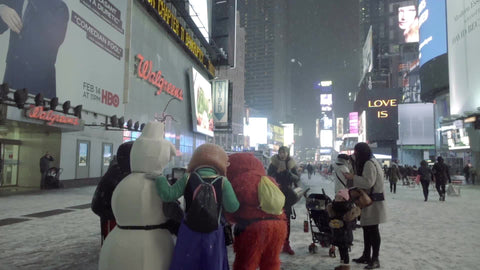 tourists with stroller taking pictures with Elmo and snowman at night in Times Square, snowing in winter in NYC