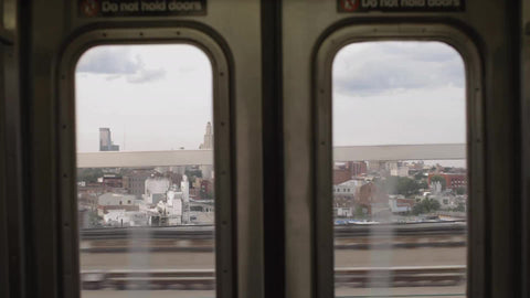 window view from elevated subway train slowing down and stopping in Brooklyn NYC
