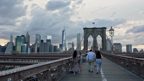 Brooklyn Bridge with Freedom Tower and Manhattan skyline at sunset with clouds in sky