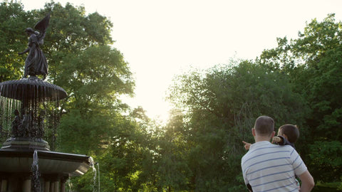 father holding his son - man and child in Central Park pointing at Bethesda statue on sunny day in summer