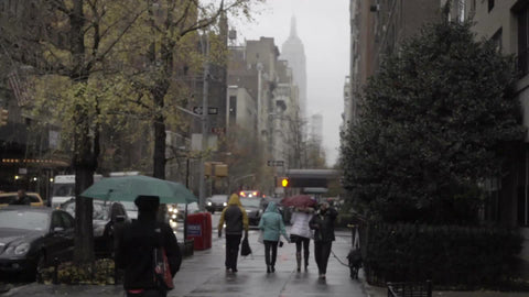 gloomy day raining on Lower 5th Avenue with people walking with umbrellas in Manhattan