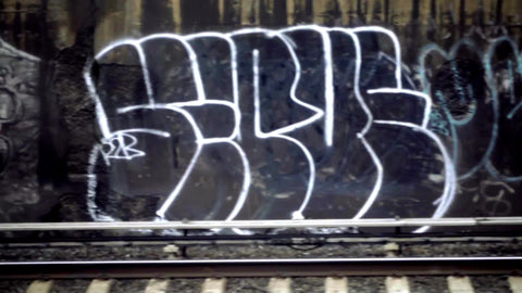 closeup of graffiti over tracks from moving subway with train passing in opposite direction in 1080 HD in NYC
