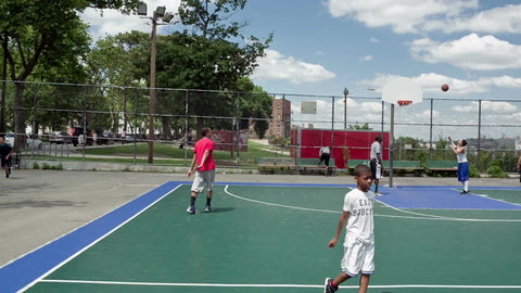 kids playing on basketball courts in New Jersey with view of Manhattan skyline on summer day