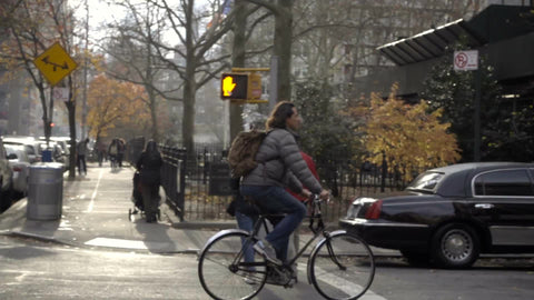 man on bicycle riding down Mercer Street past stretch limousine on street