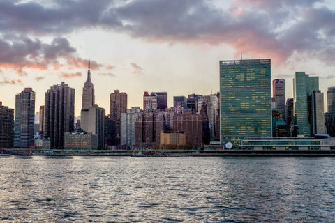 Empire State Building, United Nations, and skyscrapers in Manhattan skyline at beautiful sunset from across East River water