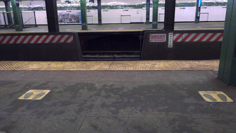 social distancing signs on floor of subway train station platform for six feet apart in NYC