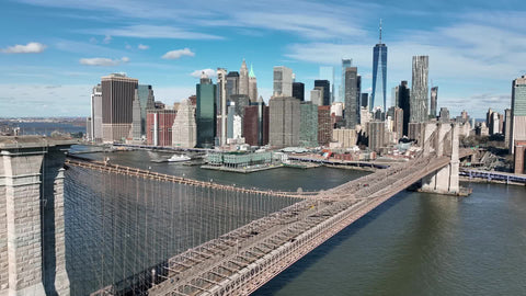 aerial moving lateral across American flag Brooklyn Bridge Manhattan skyline New York City