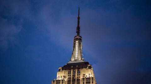 top of Empire State Building with evening lights on at night
