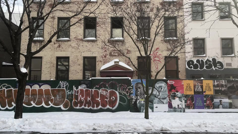 driving past graffiti on second ave in East Village from moving car snow on ground in winter Manhattan New York City NYC