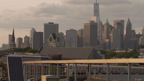 subway F train arriving at Smith-9th Streets elevated outdoor station in Brooklyn with Freedom Tower in Manhattan skyline in background