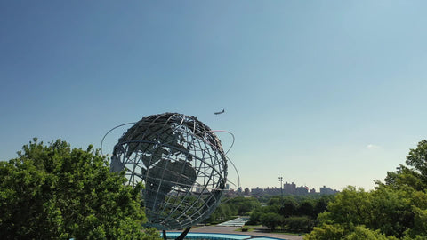 airplane flying in sky over Unisphere earth globe sculpture Flushing Queens Corona Park New York City NYC
