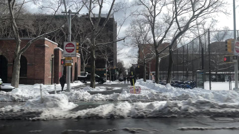 driving past cars parked next to empty park with fence and graffiti - snow in cold winter - Manhattan New York City NYC