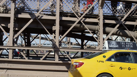 driving across Brooklyn Bridge - taxi cab crossing alongside driver's side pov with people walking on pedestrian path in 4K NYC