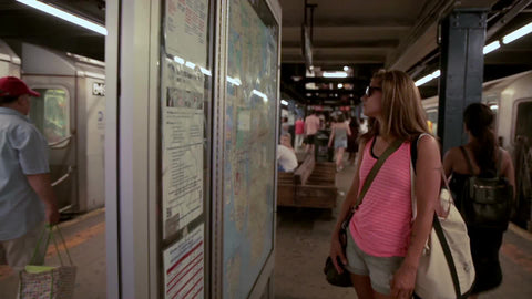 female tourist in pink tanktop and shorts in subway station looking at map