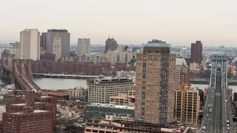 Manhattan and Brooklyn Bridge timelapse over East River with buildings on cloudy day - cars speeding in traffic
