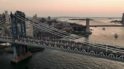 Brooklyn to Manhattan aerial skyline with cars driving across bridge at sunset New York City