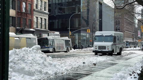 piles of snow in Manhattan winter - Grub Hub delivery man riding bicycle in street slush New York City NYC