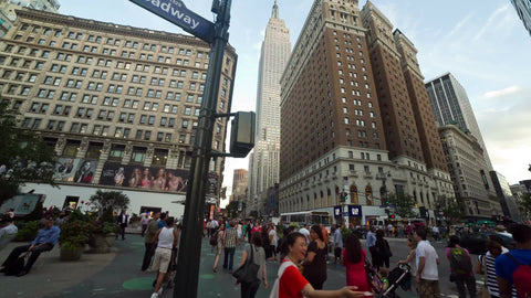 Broadway sign at Herald Square on summer day, tilting from street to Empire State Building