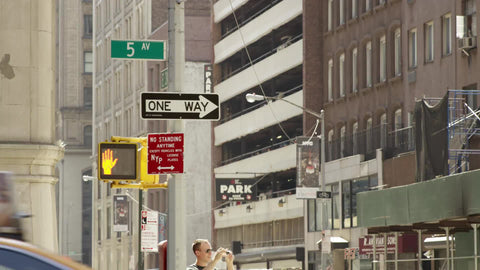 5th Avenue sign with one way arrow - taxi cab driving down Fifth Ave on summer day in Manhattan NYC