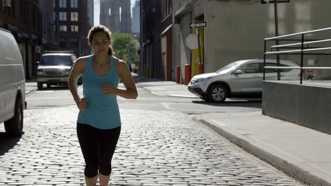 athletic woman jogging in Brooklyn on cobblestone street - 4K in slow motion NYC
