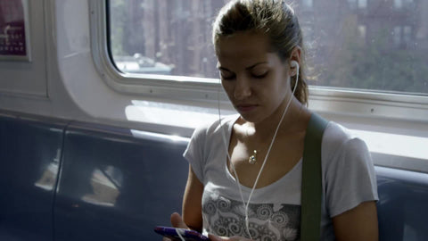 gorgeous girl on elevated train riding with earbuds on sunny summer day shining through window