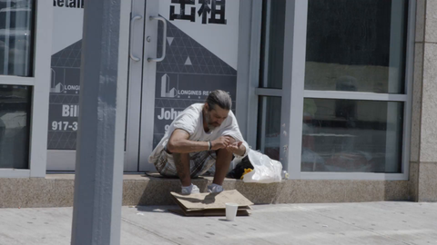 homeless man counting change on street with people walking by in 4K New York City