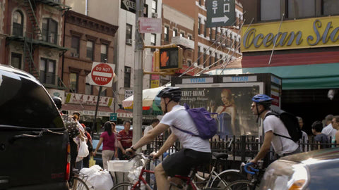 bicyclists in Chinatown on bright sunny day - people crossing street in summer