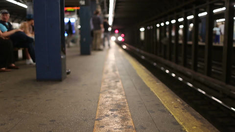 subway train entering station from low angle on platform in slow motion in NYC
