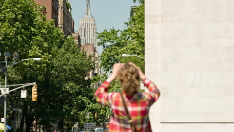 tourist taking picture of Empire State Building through famous arch in Washington Square Park on summer day in NYC