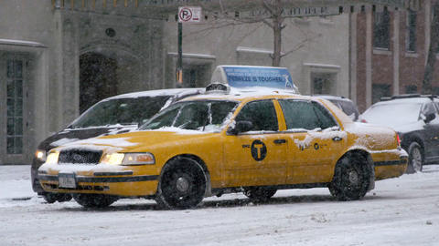 taxi cab turning corner in winter blizzard - snowing on lower 5th ave in Manhattan NYC - 4K slow motion