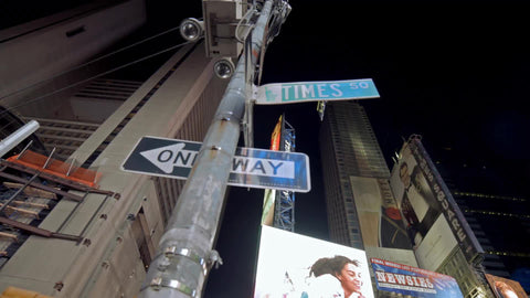 Times Square sign at night with cars driving in NYC