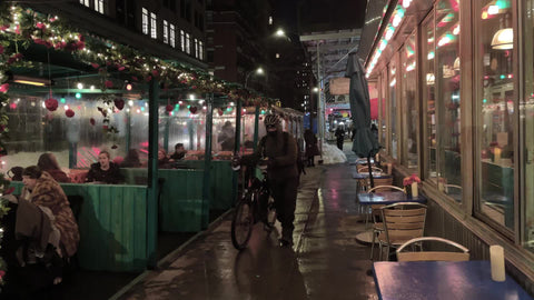 restaurant outdoor dining areas and delivery man with bicycle at night in Greenwich Village New York City NYC