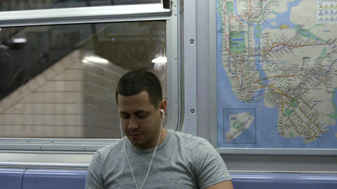 young man on subway listening to earbuds with MTA map next to him - moving train in slow motion