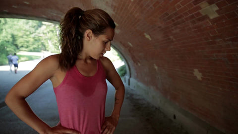 female runner stopping to catch breath under underpass in Central Park - sweating and breathing