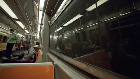 kid tuning guitar on moving subway train in summer in NYC
