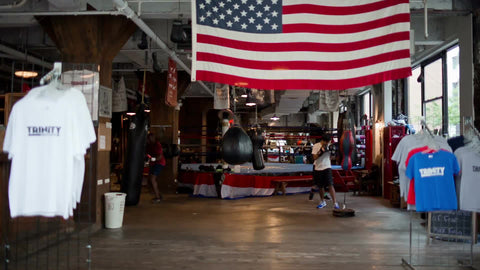 man training - hitting bag in boxing gym with American flag overhead