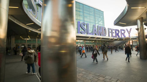 people walking in and out of Staten Island Ferry terminal during day in cold fall or spring in Manhattan NYC