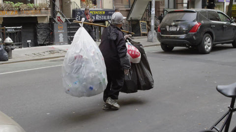 woman carrying garbage bags filled with empty soda cans in Greenwich Village