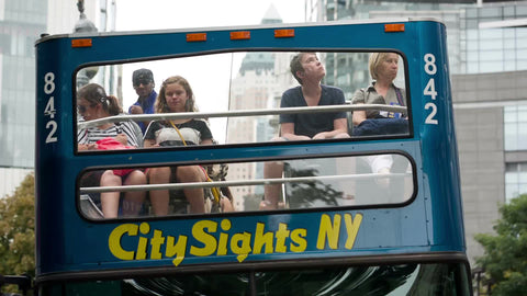 tourists on City Sights bus driving away in Midtown Manhattan NYC