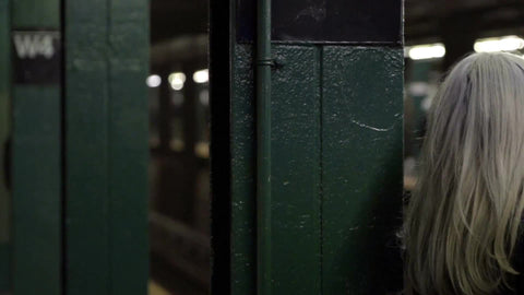woman in distress, alone, worried waiting for subway train on platform, attractive stressed girl in coat and scarf in NYC 1080